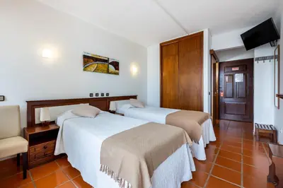a hotel room with two beds and a television at Salema Beach Hotel in Salema