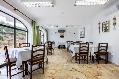 a dining room with tables and chairs and windows at Salema Beach Hotel in Salema