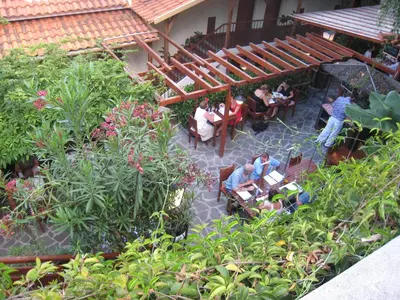 a group of people sitting at tables in a garden at Vila Ventura in Caniço