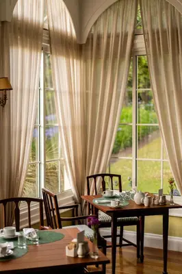 a dining room with two tables and a large window at Casa Velha do Palheiro Relais & Chateaux in Funchal