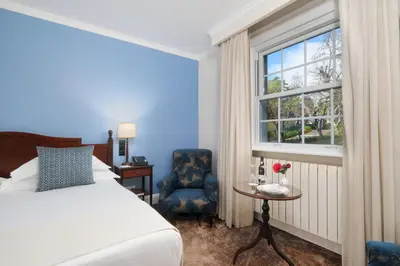 a bedroom with a bed and a window and a chair at Casa Velha do Palheiro Relais & Chateaux in Funchal