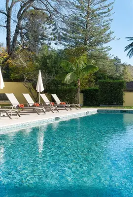 a swimming pool with lounge chairs and umbrellas at Casa Velha do Palheiro Relais & Chateaux in Funchal