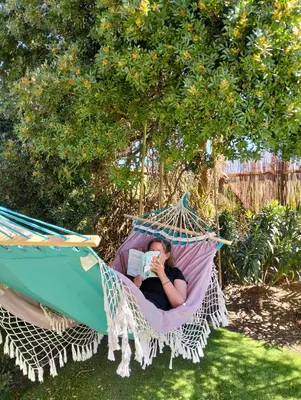 a woman sitting in a hammock reading a book at Blacksheep Sagres Guesthouse & Surf in Sagres