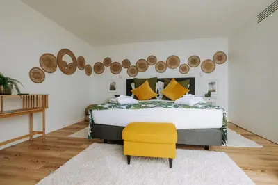 a bedroom with a bed and a yellow chair at Hotel Euro Moniz in Porto Moniz