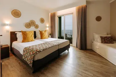 a hotel room with a bed and a balcony at Hotel Euro Moniz in Porto Moniz