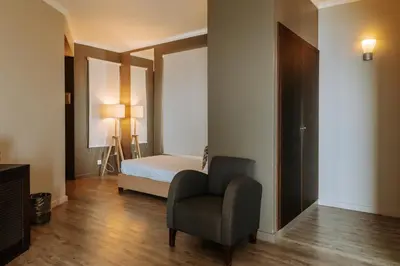 a bedroom with a bed and a chair in a room at Hotel Euro Moniz in Porto Moniz