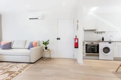 a white living room with a couch and a kitchen at Casa da Vila in Vila do Bispo