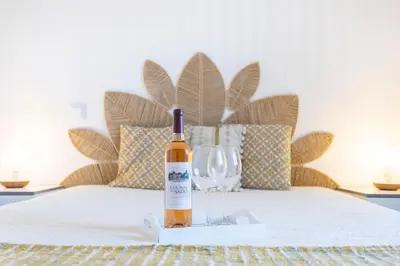 a bottle of wine and a wine glass on a bed at Casa da Vila in Vila do Bispo