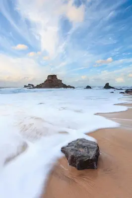 a rock sitting on a beach in the water at Casa da Vila in Vila do Bispo