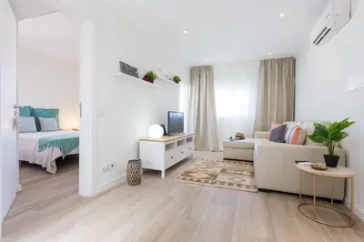 a white living room with a couch and a tv at Casa da Vila in Vila do Bispo