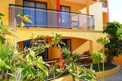 a building with a balcony with plants in front of it at Hotel Cais da Oliveira in Caniço