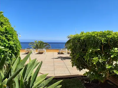 a patio with chairs and the ocean in the background at Hotel Cais da Oliveira in Caniço