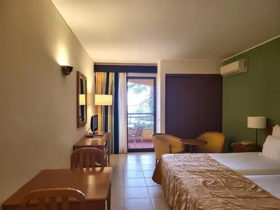 a hotel room with a bed and a table and chairs at Hotel Cais da Oliveira in Caniço