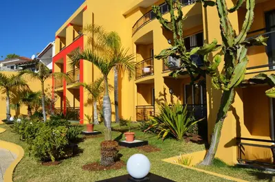 a building with palm trees in front of it at Hotel Cais da Oliveira in Caniço