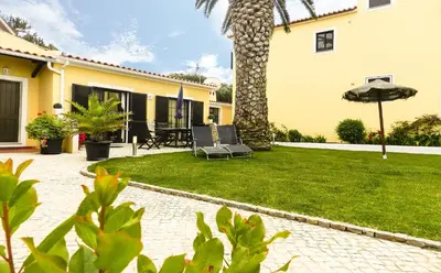 a patio with chairs and an umbrella in a yard at Residencia Julio in Sagres