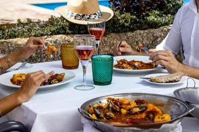 a group of people sitting at a table with plates of food at Pousada de Sagres in Sagres