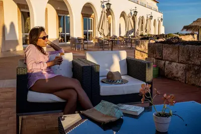a woman sitting in a chair with a drink at Pousada de Sagres in Sagres