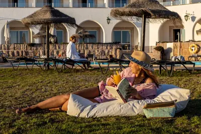 a woman laying on the grass reading a book at Pousada de Sagres in Sagres