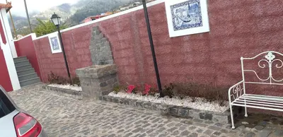 a bench sitting next to a red brick wall at the old school in Calheta