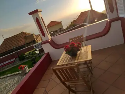 a balcony with a table and a chair and flowers at the old school in Calheta