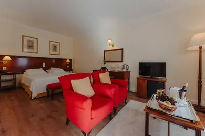 a hotel room with a bed and two red chairs at Quinta da Bela Vista in Funchal