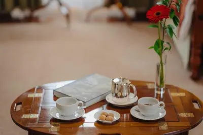 a table with two coffee cups and a vase with a flower at Quinta da Bela Vista in Funchal