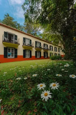 a building with black windows and flowers in the yard at Quinta da Bela Vista in Funchal