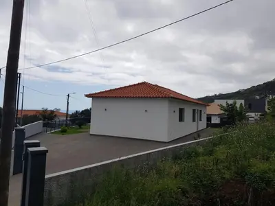 a white building with a red roof on a street at migs'place in Arco da Calheta