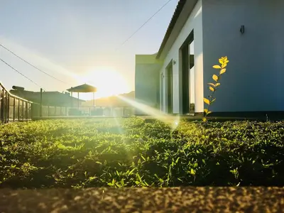 a house with the sun shining on the grass at migs'place in Arco da Calheta