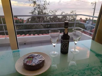 a bottle of wine and a cake and glasses on a table at Canto da Manu Panoramic in Calheta