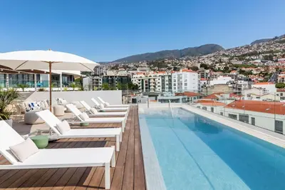 a couple sitting on a couch looking out over a city at Hotel Orquidea in Funchal