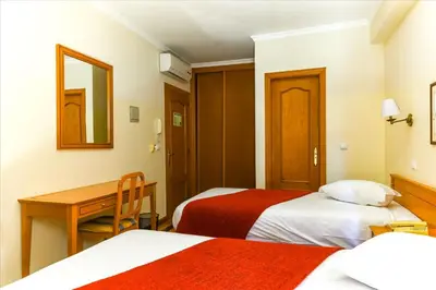 a hotel room with two beds and a desk at Residencial Colombo in Funchal