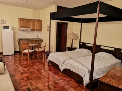 a bedroom with a canopy bed and a kitchen at Residencial Colombo in Funchal
