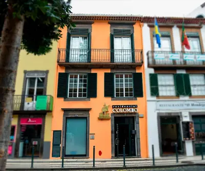 an orange building with black shutters on a street at Residencial Colombo in Funchal