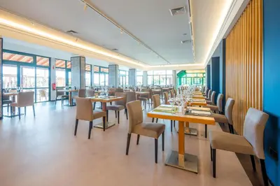 a dining room with tables and chairs and windows at Sentido Galosol in Caniço