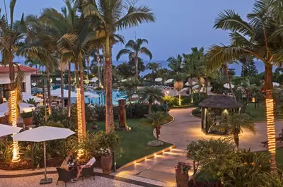 a view of a resort with palm trees at night at Suite Hotel Eden Mar - PortoBay in Funchal