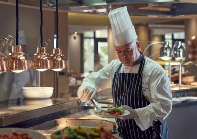 a chef preparing a plate of food in a kitchen at Suite Hotel Eden Mar - PortoBay in Funchal