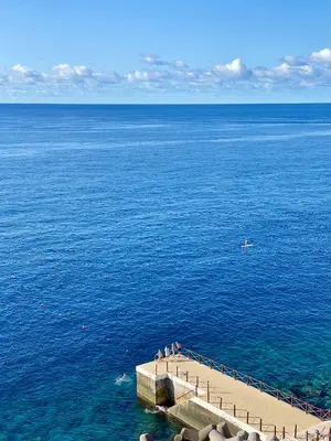 a group of people standing on a pier in the water at The Cliff Bay - PortoBay in Funchal