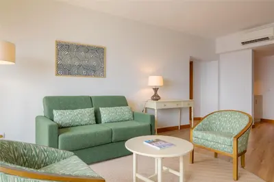 a living room with a green couch and a table at Pestana Vila Lido Madeira Ocean Hotel in Funchal