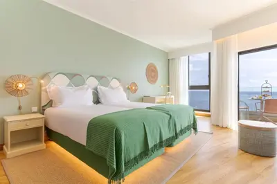 a bedroom with a large bed and a large window at Pestana Vila Lido Madeira Ocean Hotel in Funchal