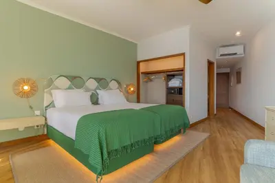 a bedroom with a large bed with a green blanket at Pestana Vila Lido Madeira Ocean Hotel in Funchal