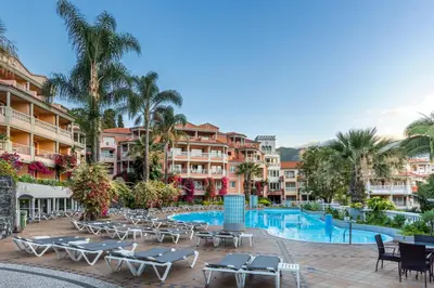 a resort with a pool and chairs and palm trees at Pestana Miramar Garden & Ocean Hotel in Funchal