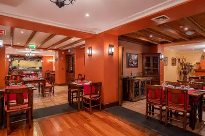 a restaurant with orange walls and wooden tables and chairs at Pestana Miramar Garden & Ocean Hotel in Funchal