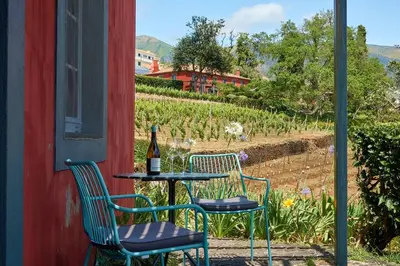 two chairs and a table with a bottle of wine at Quinta das Vinhas in Calheta