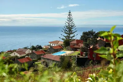 a house with a swimming pool in front of the ocean at Quinta das Vinhas in Calheta