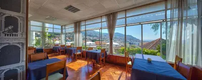 a restaurant with tables and chairs and large windows at Hotel Monte Carlo in Funchal