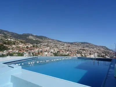 a large swimming pool with a city in the background at Hotel Monte Carlo in Funchal