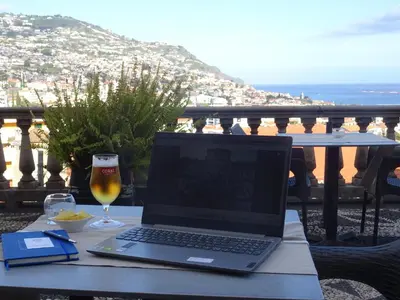 a laptop computer sitting on a table with a glass of beer at Hotel Monte Carlo in Funchal