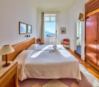 a bedroom with a large white bed and a window at Hotel Monte Carlo in Funchal