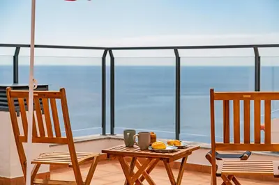 a table and chairs on a balcony with a view of the ocean at Apartamento Lobo Marinho by An Island Apart in Santa Cruz